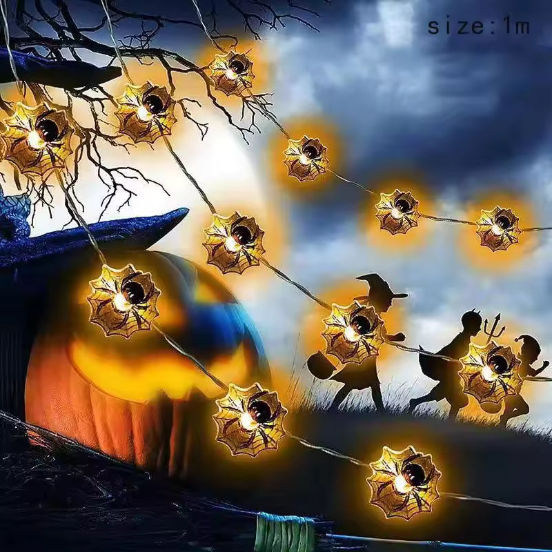 Halloween-themed string lights with pumpkins, witch hats, and ghosts against a dark sky.